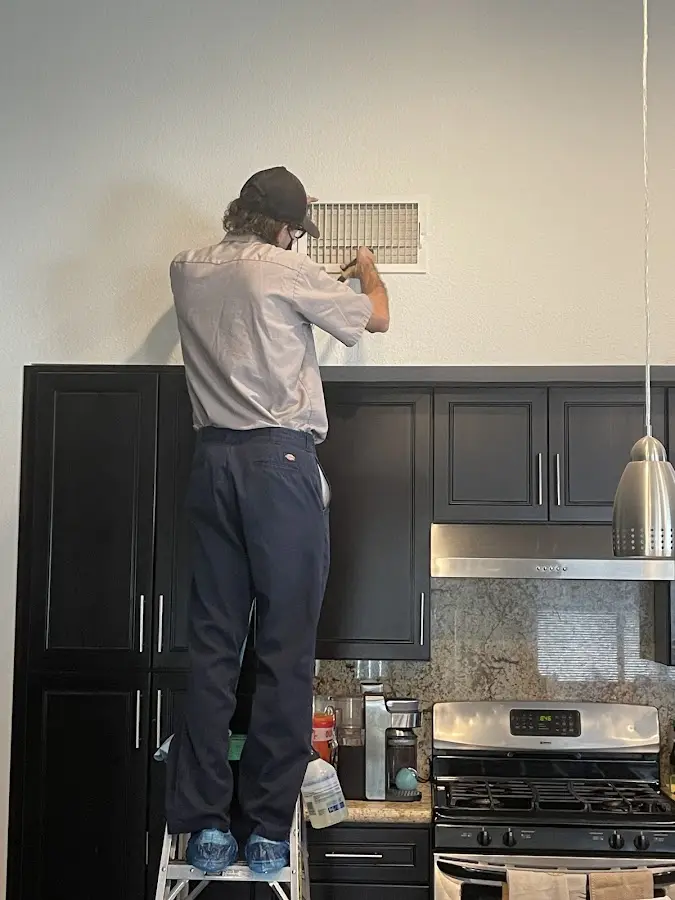 Technician inspecting an air vent during HVAC service in Garfield